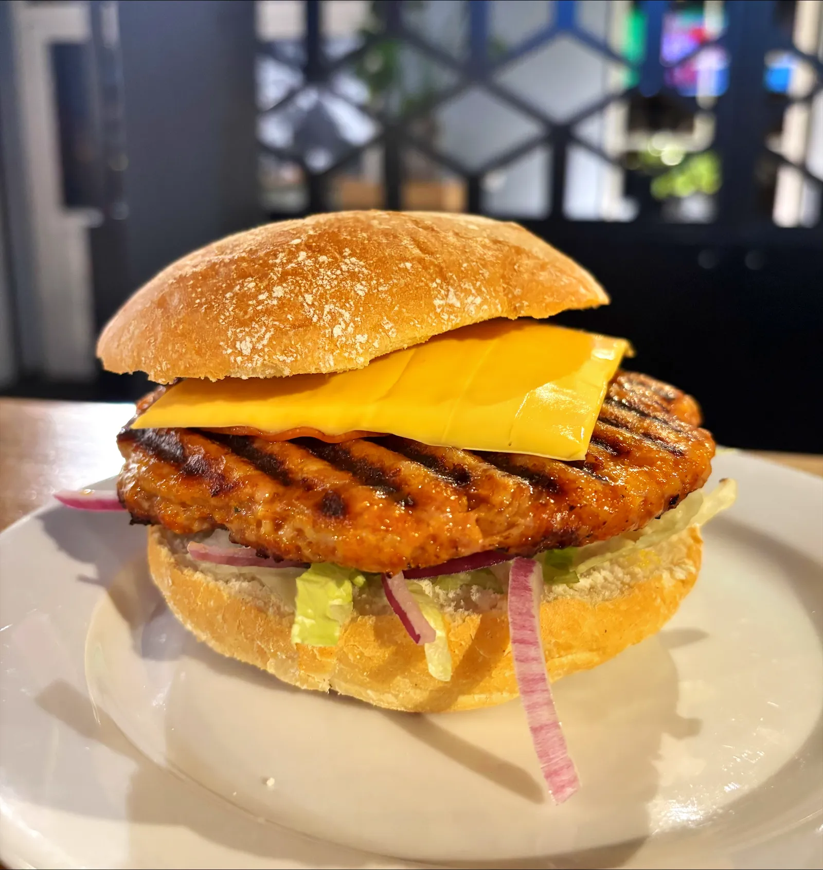 Gegrilde burger met kaas, sla en rode ui op een bol broodje